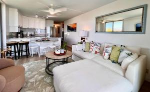 a living room with a white couch and a kitchen at Puako Penthouse 409 - Top Floor Unit - Pool in Puako