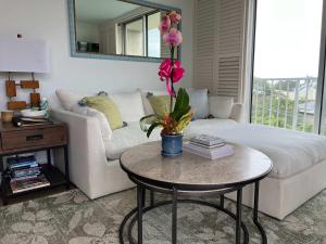 a living room with a white couch and a table with a flower at Puako Penthouse 409 - Top Floor Unit - Pool in Puako +15 photos