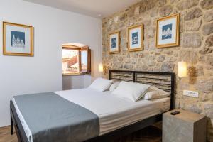 un dormitorio con una cama y una pared de piedra en Villa Four Winds, en Dubrovnik