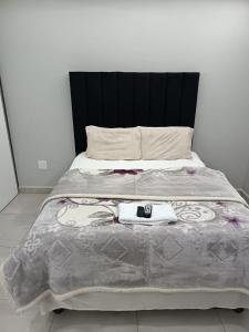 a bed with a black headboard and a towel on it at New Hillcrest centre guest House in Kimberley +8 photos