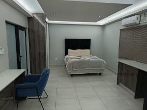 a bedroom with a bed and a blue chair at New Hillcrest centre guest House in Kimberley