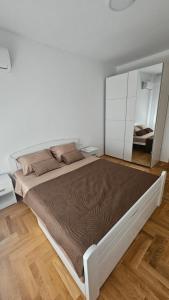 a large bed in a white room with a mirror at Apartman E&A in Radanovići