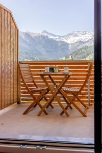 a wooden table and chairs on a balcony with mountains at Chuenislodge3 neu&stilvoll, 2Balkone, echtes Bijou mit top-Aussicht in Adelboden