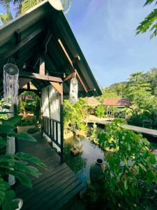 a house with a pond in front of it at Watermelon House at Nong Thale Garden & Kitchen in Ban Khao Klom