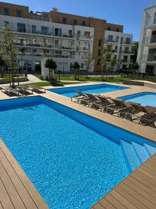 a swimming pool with chairs in front of a building at Szum Bałtyku in Jastrzębia Góra