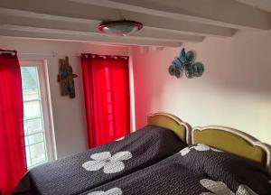 a bedroom with a bed with red curtains and a window at Maison atypique et confortable in Mamers