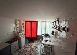 a small kitchen with a table and red curtains at Maison atypique et confortable in Mamers