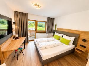 a bedroom with a bed and a desk and a television at Gasthof Alpenblick in Tobadill