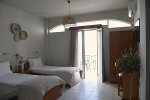 a bedroom with two beds and a large window at Venus Studios in Vlachata