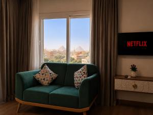 a living room with a green couch in front of a window at La Veranda Pyramids View Hotel in Cairo