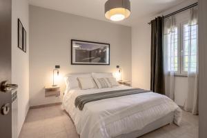 a white bedroom with a large bed and a window at Casa Le Camelie idromassaggio e relax Lucca in Capannori