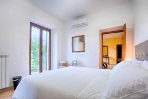 a white bedroom with a white bed and a window at Fons Clara Domus et Eventi in Fontechiari
