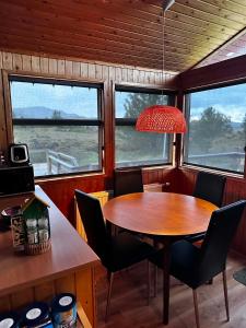 a dining room with a table and chairs and windows at A cosy 2 bedroom cabin with an amazing view in Borgarnes