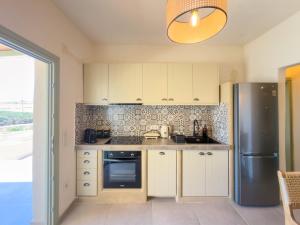 a kitchen with white cabinets and a stainless steel refrigerator at Mikres Cyclades - Koufonisia House in Koufonisia +11 photos