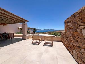 a patio with two chairs and a stone wall at Mikres Cyclades - Koufonisia House in Koufonisia