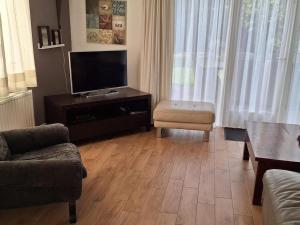 a living room with a flat screen tv and a chair at Bungalow in Breskens near Beach & Lighthouse in Breskens