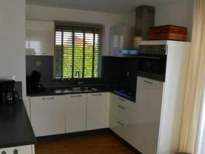 a kitchen with white cabinets and a sink and a window at Bungalow in Breskens near Beach & Lighthouse in Breskens