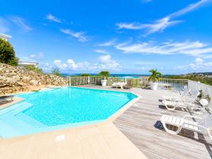 a swimming pool on a deck with chairs and the ocean at Studio ALIZEA in Saint Martin