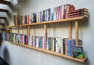 a book shelf filled with books on a wall at The Lodge at Wah, Palampur in Pālampur