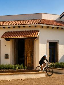a person riding a bike in front of a house at Hotel Hacienda Concá in Conca