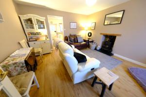a living room with a white couch and a fireplace at Rose Cottage in Buxton