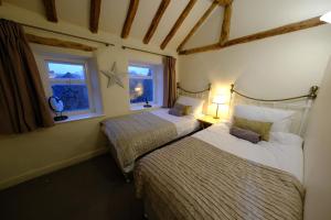 two beds in a room with two windows at Rose Cottage in Buxton