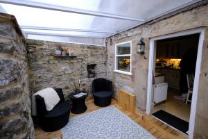 a room with two chairs and a stone wall at Rose Cottage in Buxton