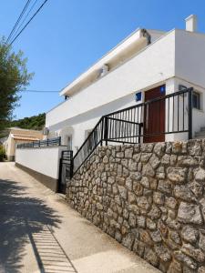 a stone wall in front of a white house at Croatia Apartman Masa in Senj