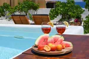 two glasses of wine and fruit on a table next to a pool at Mandrakia Living House in Mandrakia