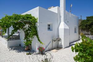a white building with a tree in front of it at Mandrakia Living House in Mandrakia