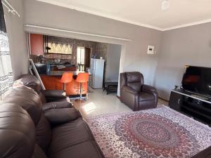 a living room with a leather couch and a television at The Marina Suite in Mbabane