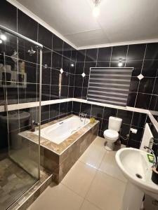 a bathroom with a tub and a toilet and a sink at The Marina Suite in Mbabane