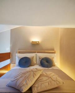 a bed with two blue pillows on top of it at Tiny Park House in Sabaudia +15 photos