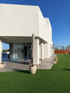 a white house with a green lawn and a plant at Amalfi Apart in Villa María