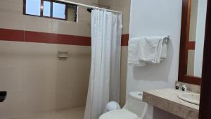 a bathroom with a white shower curtain and a toilet at HOTEL XIADANI Restaurante, Temazcal & Spa in Tlaxcala de Xicohténcatl +44 photos
