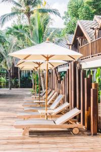 a row of beach chairs with umbrellas on a dock at Burapha hotel in Ban Ta Sang
