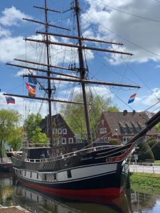 a sail boat docked in the water next to houses at Fehn Appartement II - Stay Apartment nahe Zentrum, Küche, Parkplatz & Highspeed WLAN in Papenburg +8 photos