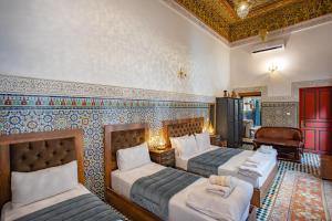a bedroom with three beds and a room with a couch at Dar Iline - RoofTop in Fez