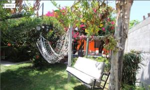 a white hammock in a garden with flowers and plants at NEW Hotel Casa del Profesor in Iquique