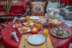 a red table topped with plates of food and orange juice at Dar Iline - RoofTop in Fez
