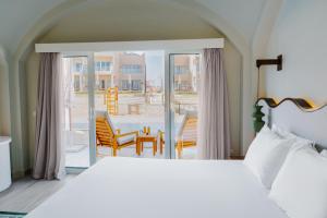 a bedroom with a bed and a view of a patio at Diamond Beach By Pearl Resort in Quseir