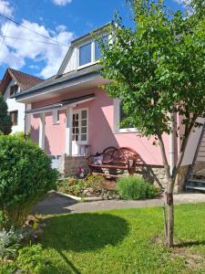a pink house with a tree in the yard at Chalupa u Strakov in Lúčky