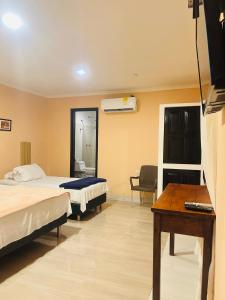 a hotel room with two beds and a desk at Hotel Galeria la Trinidad in Cartagena de Indias