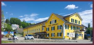 een geel gebouw met een auto ervoor geparkeerd bij Hotel Römerbad in Zofingen