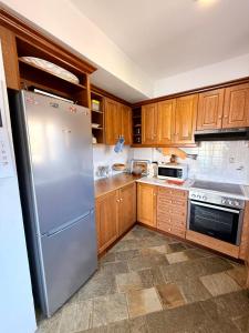 a kitchen with wooden cabinets and a stainless steel refrigerator at Aegean Big Blue -Rosalie Home in Tinos