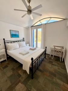 a bedroom with a large bed with a ceiling fan at Aegean Big Blue -Rosalie Home in Tinos