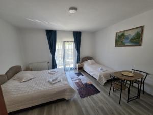 a bedroom with two beds and a small table at NP Luxury Apartments in Novi Pazar