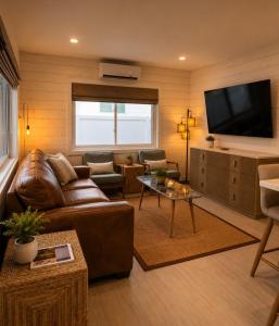 a living room with a leather couch and a flat screen tv at Blue Wave Suites in Clearwater Beach