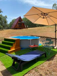 a pool with a table and an umbrella at El Roble Glamping - Cabaña Alpina - Pet Friendly in Lagunilla