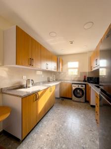 a kitchen with wooden cabinets and a washer and dryer at Elite hotel in Sheikh Zayed